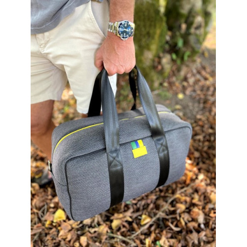 Sac week-end écoresponsable homme en cuir et tissu recyclé porté épaule et main gris